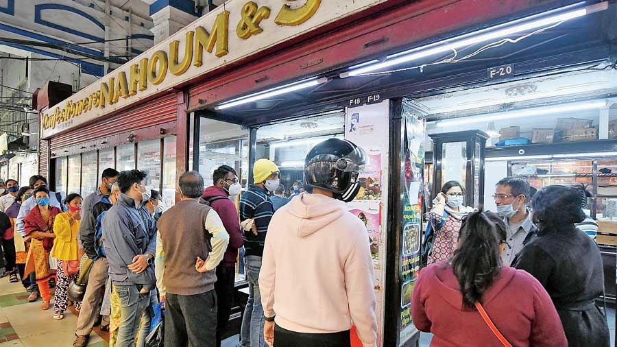 Customers queue up for Christmas cakes outside Nahoum’s in New Market on Thursday evening.