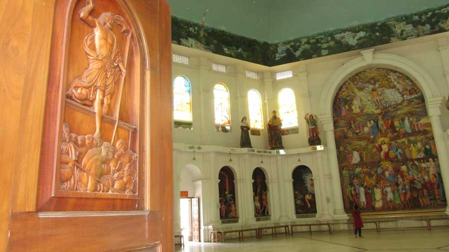 A massive wooden door with an engraved figure of Christ welcomes people in