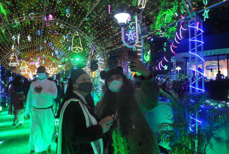 JOY TO THE WORLD: A woman takes a selfie with a nun on Monday, December 20, at Allen Park on Park Street ahead of Christmas 2022. Like every year, the dine-drink-dance street has been transformed into a fairyland with myriad colourful lights, giant models of Santa Claus and Xmas trees to celebrate the season of gifts. Giant bells, stars and rings made of LED lights have been hung from the trees lending them a mesmerising look