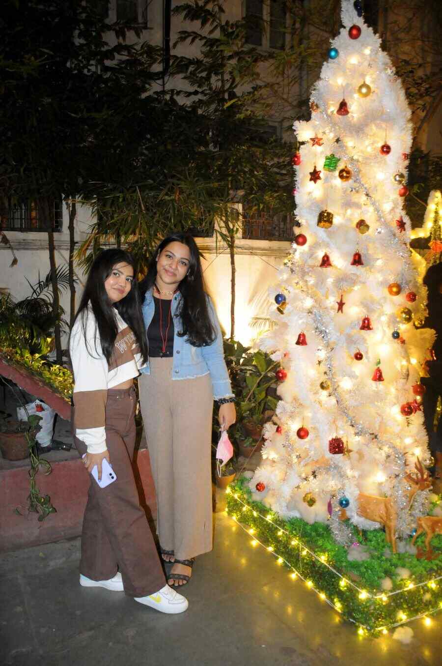 School friends Ronica Balmiki (L) and Debanjali Roy Choudhury pose in front of the unique Christmas tree at Roastery Coffee House while waiting for a table