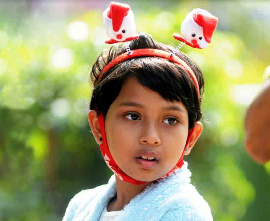 The simple joys of a Christmas Day outing reflect in the eyes and face of a young girl sporting a fancy Santa headgear and a matching red mask at Alipore zoo