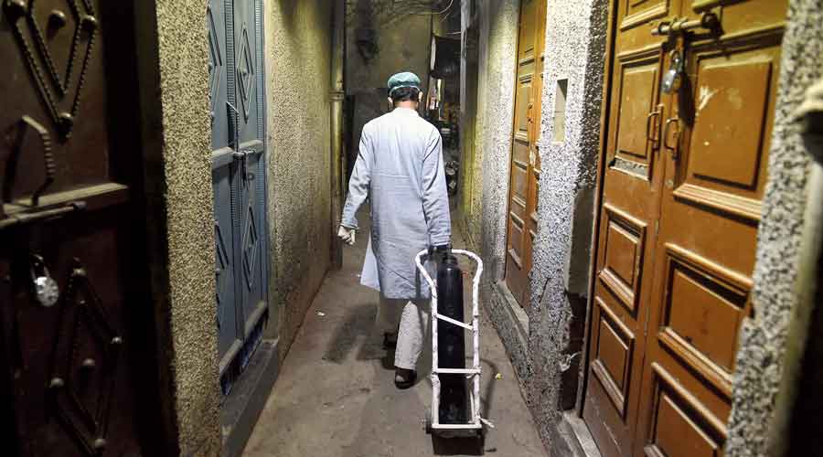A patient’s relative arrives to have an oxygen  cylinder refilled late at night on April 30, 2021, in the Walled City area of New Delhi.