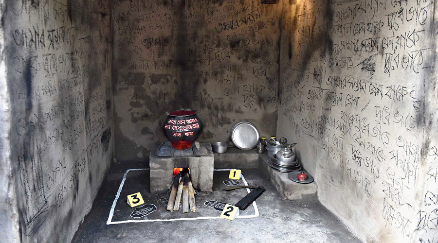 A village kitchen with poetry on the wall about a mother worrying about the scarcity of food for her children because of the Centre’s three new farm laws (marked on the floor).
