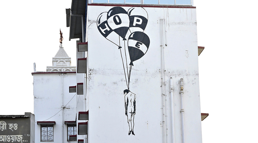 A facade shows a man hanging from balloons which read “HOPE”.