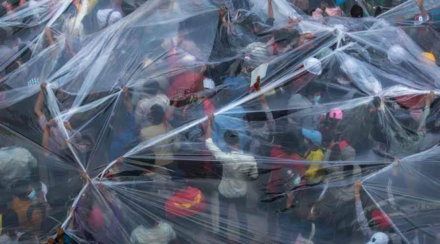Demonstrators use plastic sheets to protect themselves in case the security forces fired water cannons in Yangon