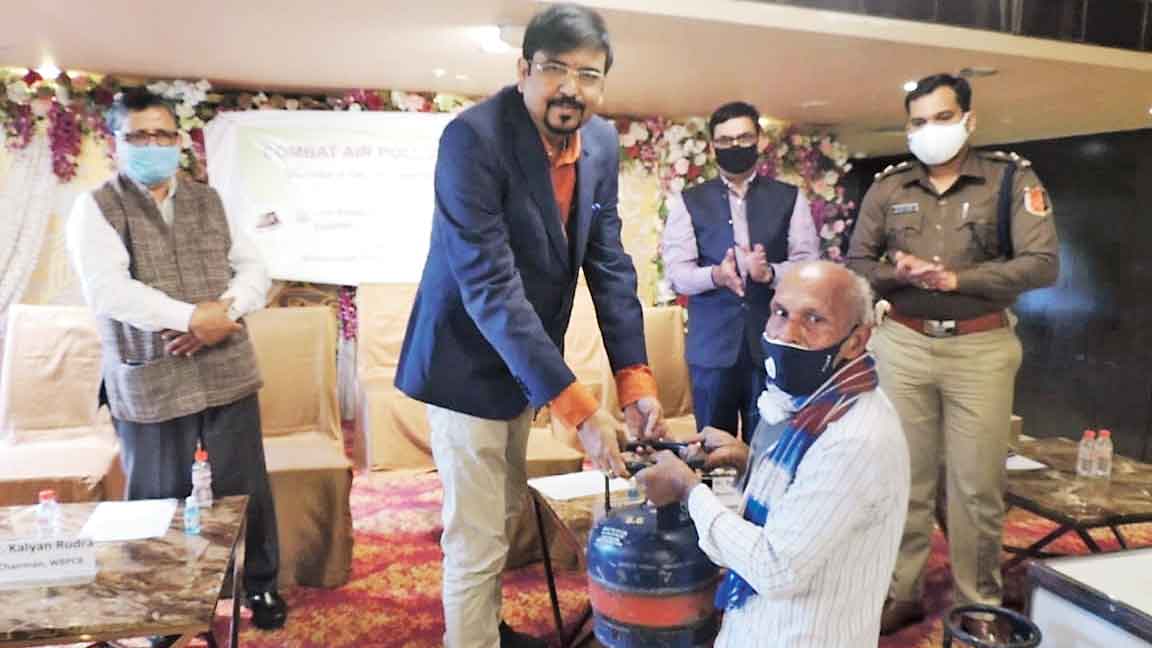 Fire and emergency services minister Sujit Bose hands over a cylinder to an ironer at a programme in Lake Town as (left) PCB chairman Kalyan Rudra looks on