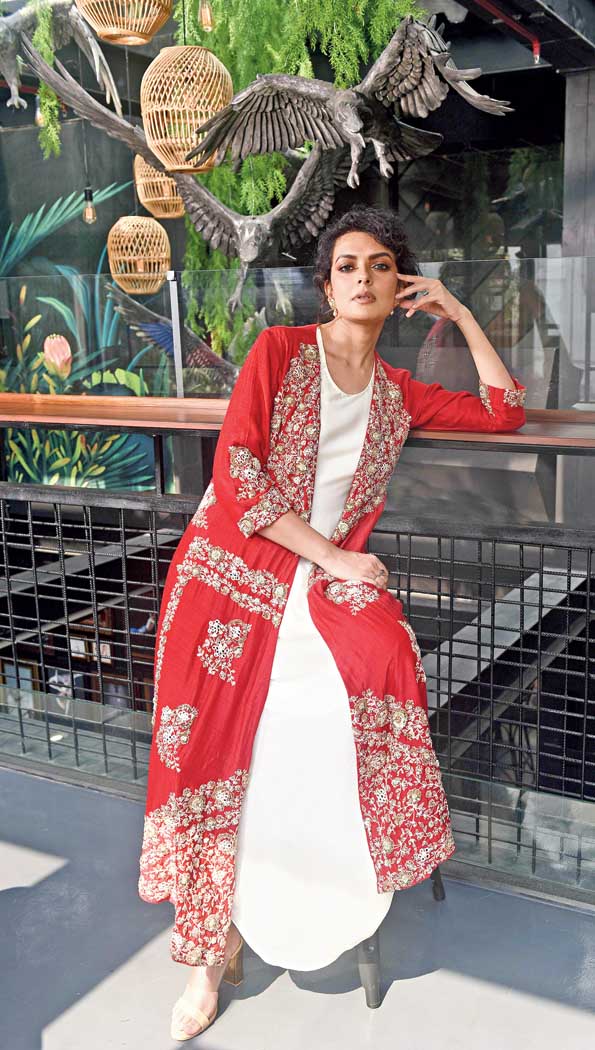 There is something effortless about this draped off-white dress teamed with a red embroidered jacket that is embellished with mirror embroidery in floral patterns