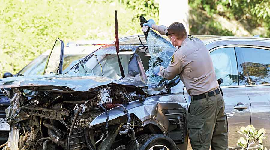 A law enforcement officer looks over the damaged vehicle being driven by Tiger Woods following the rollover accident in Los Angeles on Tuesday