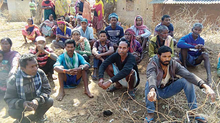 Villagers sit outside the house of the victims.