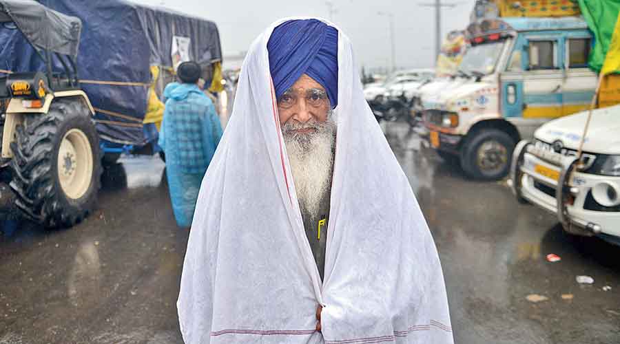 An elderly farmer braving rain.