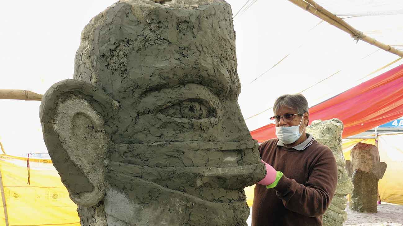 Rupchand Kundu puts finishing touches on one of the masked faces at Akankha More.