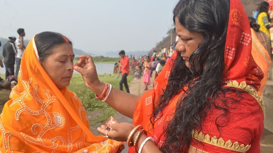 A woman applies 'sindoor' on the forehead of another woman, as part of a holy ritual, on the bank of river Damodar at Mohalbani Ghat in Dhanbad on Thursday.