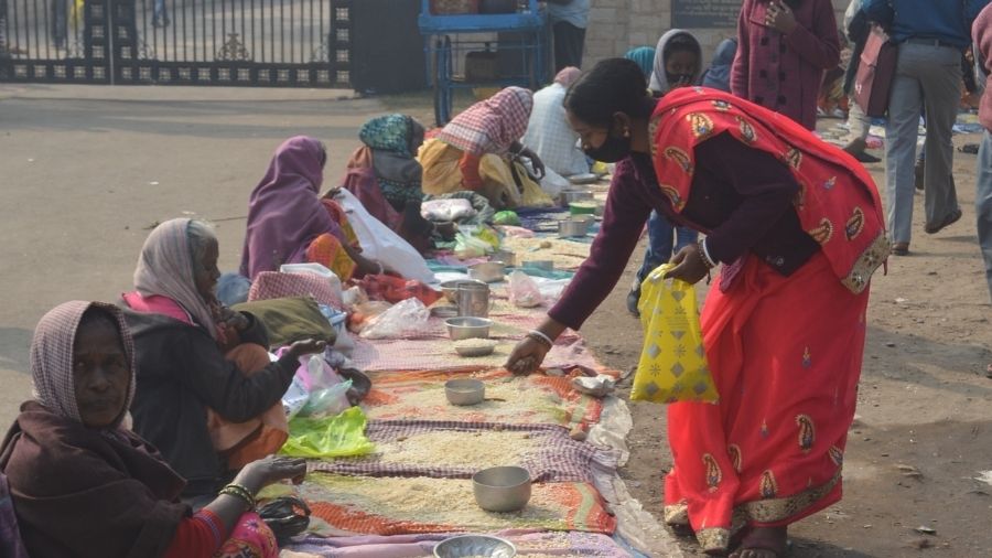 A devotee donates food grain, clothes and money to people from the economically weaker sections of the society, after taking the holy dip in river Damodar, at Mohalbani Ghat in Dhanbad on Thursday.