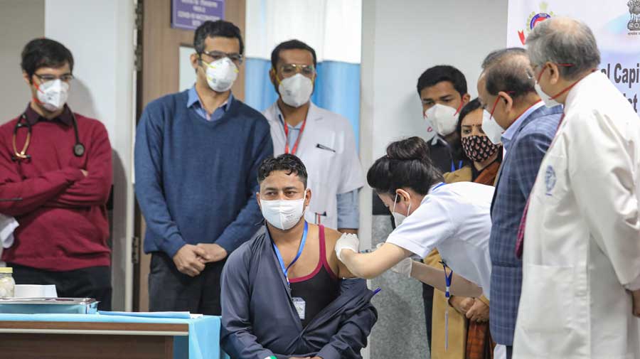 A medic administers the first dose of Covishield vaccine to a frontline worker in the presence of health minister Harsh Vardhan at AIIMS in New Delhi on Saturday.