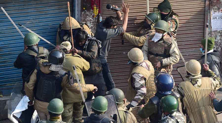 Security personnel baton charge a protester during clashes after farmers tractor rally turned violent