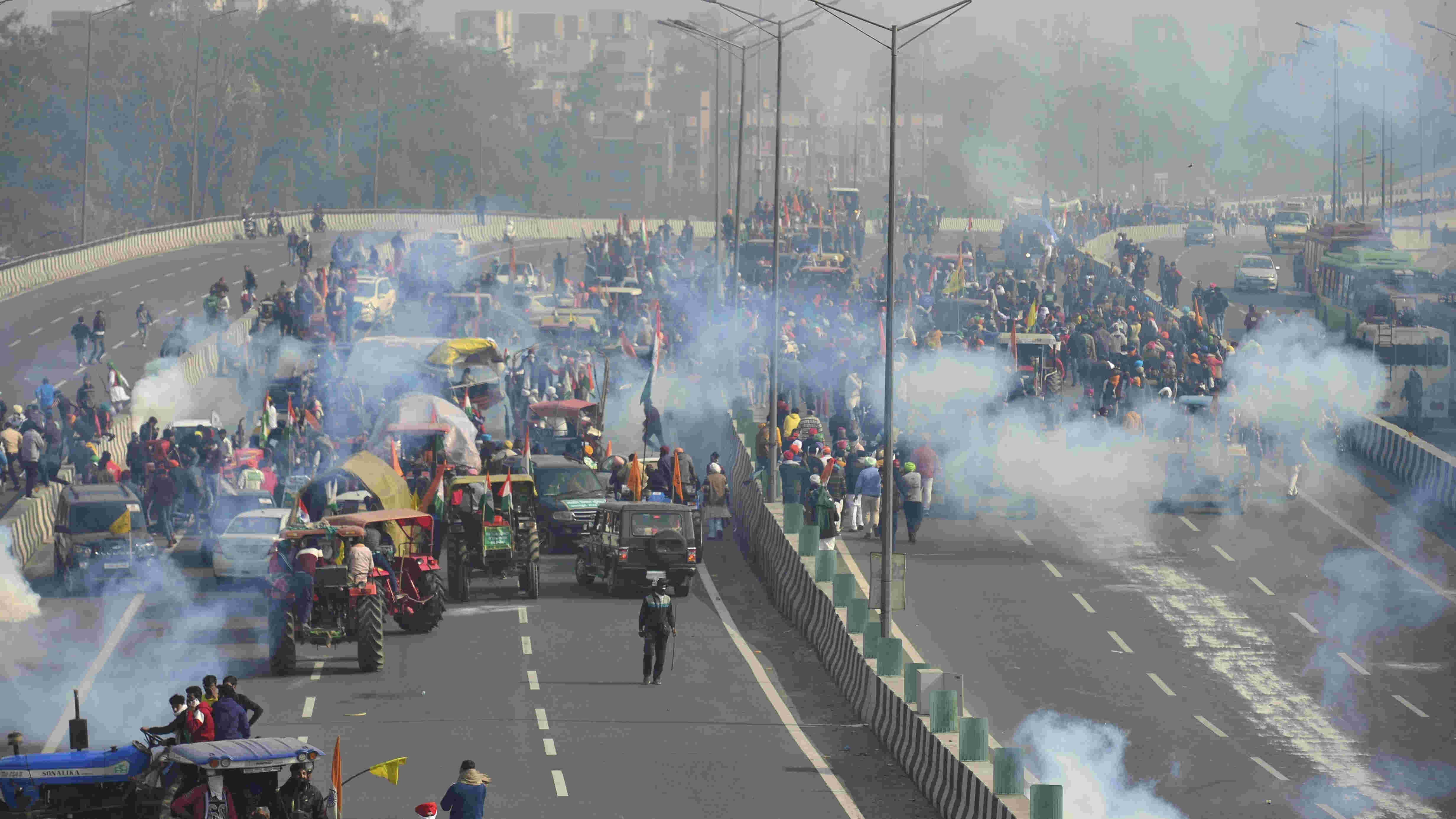 Police fire teargas shells to disperse protesting farmers who were attempting to break barricades at Ghazipur border during their tractor march on Republic Day, in New Delhi, Tuesday, Jan. 26, 2021.
