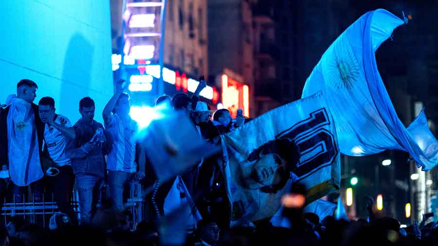 Fans gather at the Obelisk in Buenos Aires, waving a Maradona-inscribed flag to celebrate the win