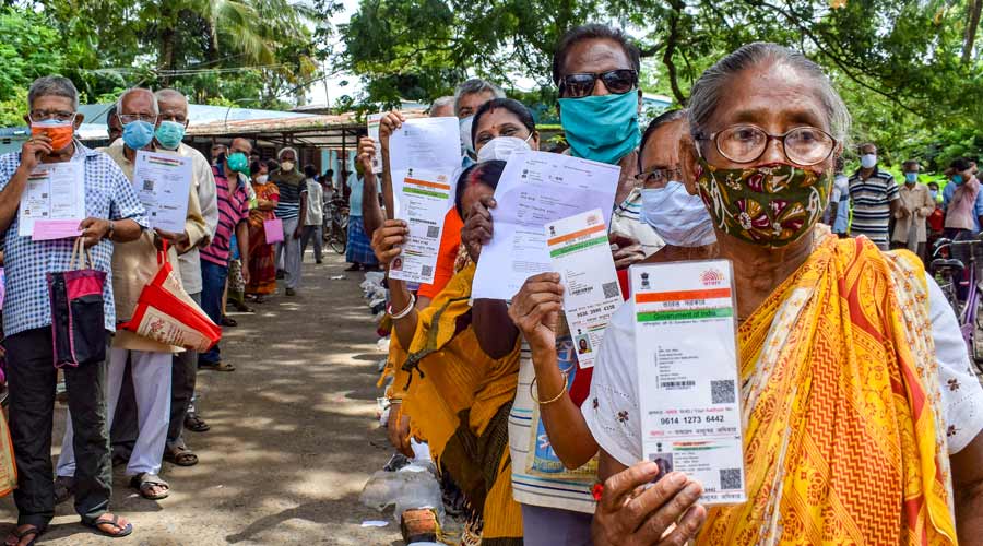 Beneficiaries show their Aadhar card and ragistration form wait in a long queue to receive a dose of COVID-19 vaccine at a vaccination centre in Nadia on Wednesday.