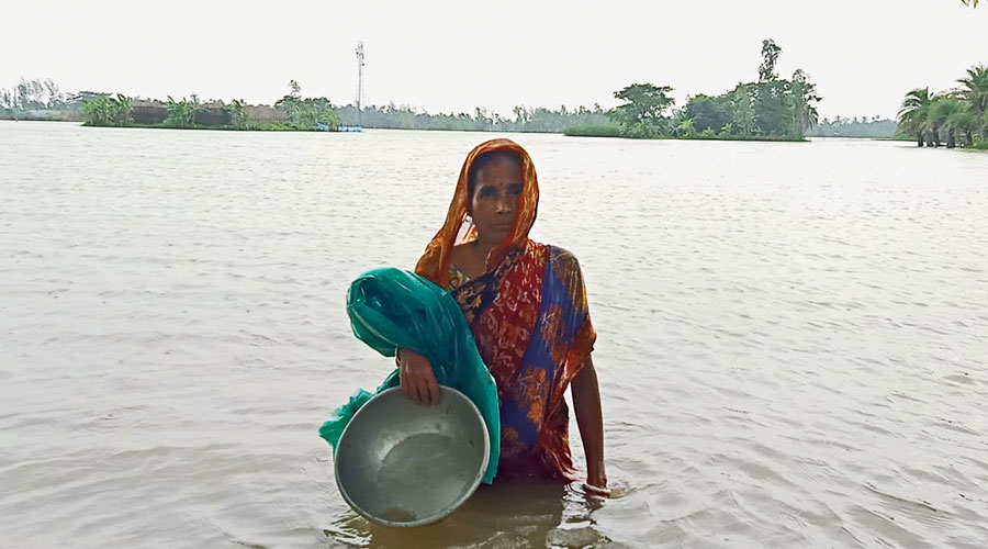 A woman wades through floodwater in a village of South 24-Parganas. 