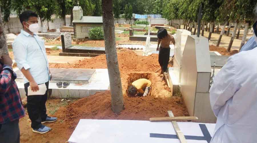 Workers dig a grave at the cemetery in Bhubaneswar 