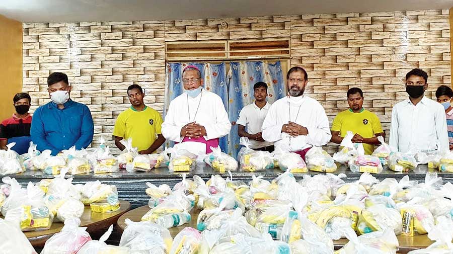 Archbishop Felix Toppo (in blue mask) prays before the distribution of food packets  among Covid patients at RIMS Ranchi. 