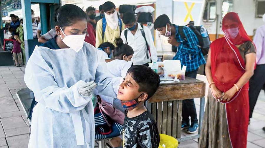 A health worker takes the swab sample of a boy for a Covid-19 test at Dadar railway station  in Mumbai on Thursday. 