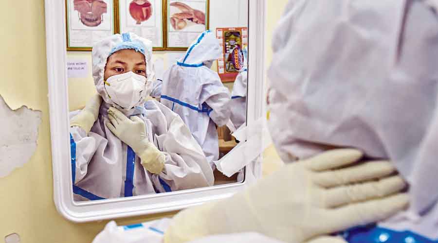 A nurse adjusts her mask by looking  in the mirror