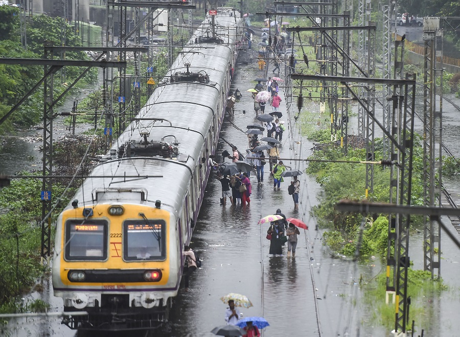 Stranded local train commuters walk on the waterlogged railway tracks during rain, at Kurla, in Mumbai on Wednesday.