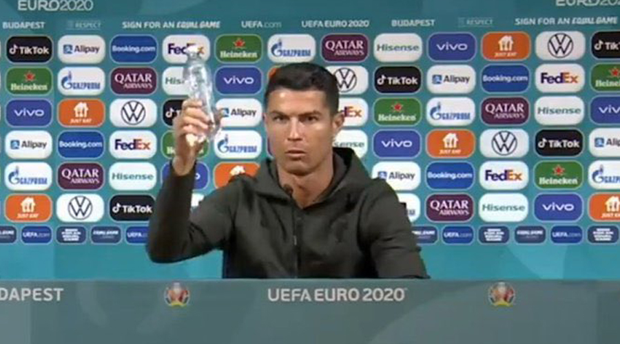Cristiano Ronaldo holds up the bottle of water after pushing away the Coca-Cola bottles away on Monday. 