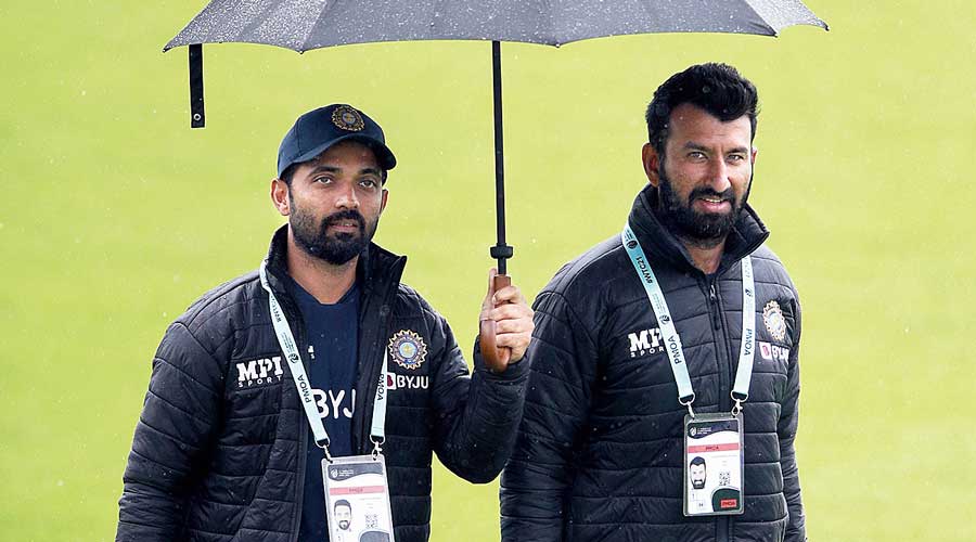 Ajinkya Rahane (left) and Cheteshwar Pujara walk across the field in Southampton on Monday. Rain washed out the entire fourth day’s play. 