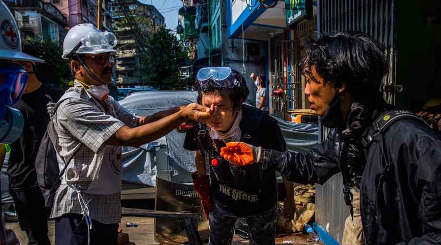 Volunteer medics help protesters wash their faces after security forces used tear gas to disperse people demonstrating against the military coup, in Yangon