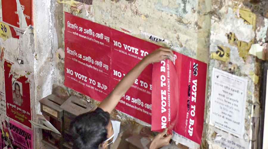 Campaigners paste ‘No Vote to BJP’ posters on the walls of the Coffee House building