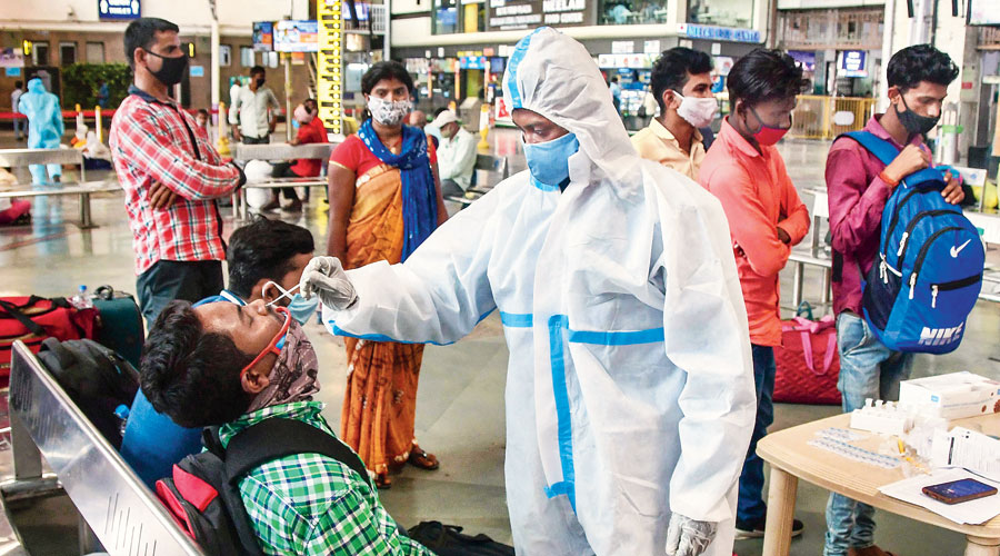 A health worker takes a swab sample from a passenger at the CSMT station  in Mumbai on Wednesday. 