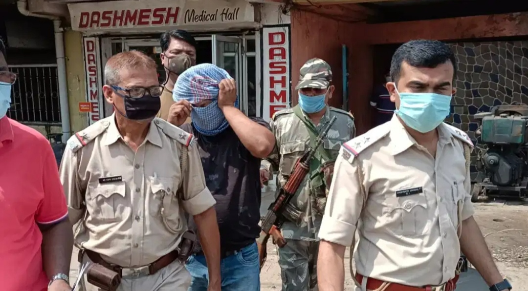 Owner of the medical store (face covered) after being arrested by police on Dimna Road in Mango on Monday. 