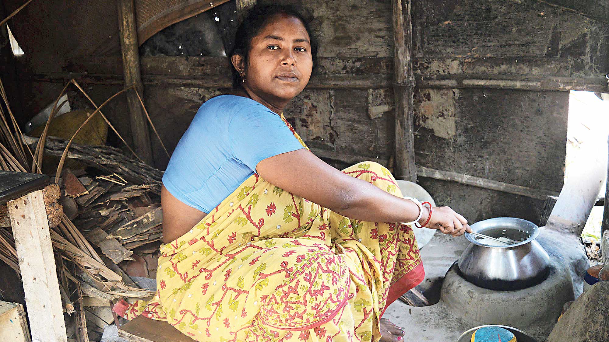 Chandra Sarkar cooks in her shanty home by Kestopur Canal that got ravaged by Cyclone Amphan.