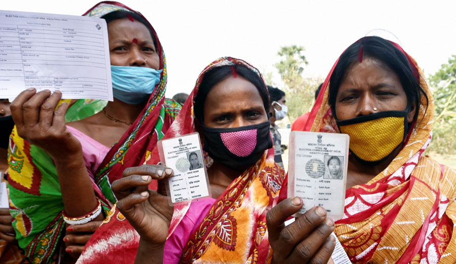 Women show thier voter identity cards outside a polling station during the first phase of West Bengal Assembly elections, at Chandrapur in Lalgarh on Saturday.