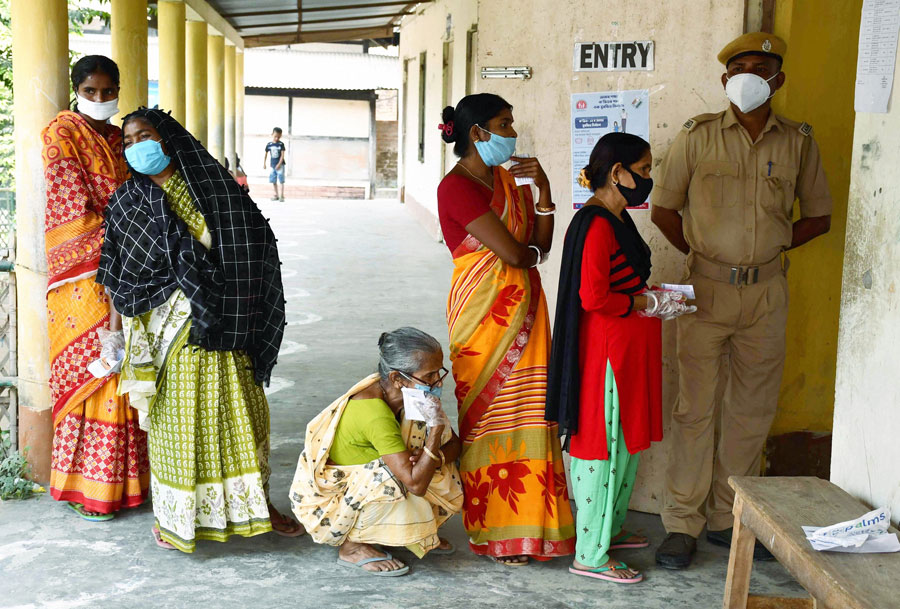 Voters queue up outside a polling station during the first phase of polling for Assam Assembly elections, at Rupohi in Nagaon district on Saturday.
