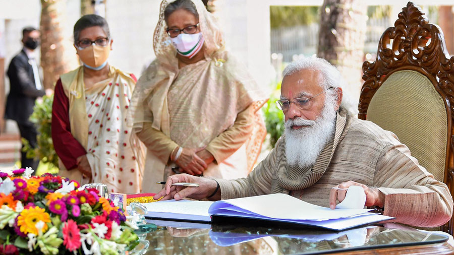 Narendra Modi writes in the visitors book after paying tribute at the mausoleum of Bangabandhu Sheikh Mujibur Rahman, at Tungipara on Saturday.