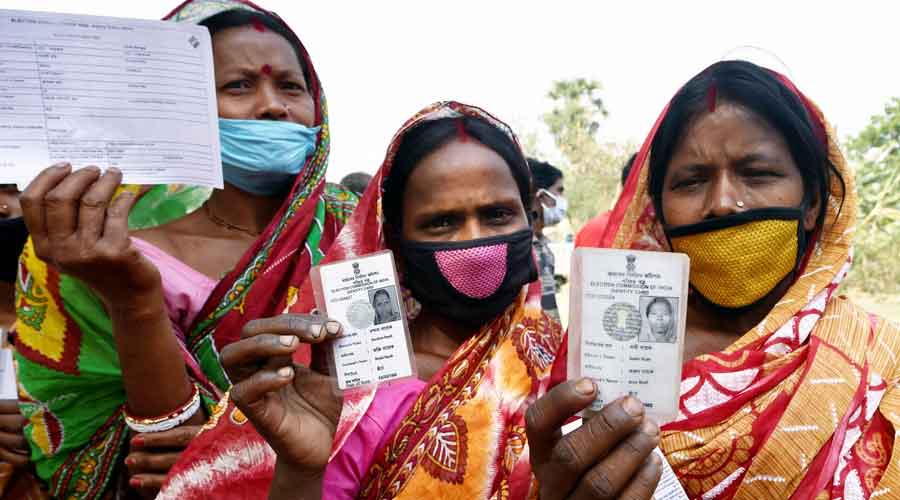 Women show thier voter identity cards outside a polling station during the first phase of West Bengal Assembly elections, at Chandrapur in Lalgarh on Saturday.