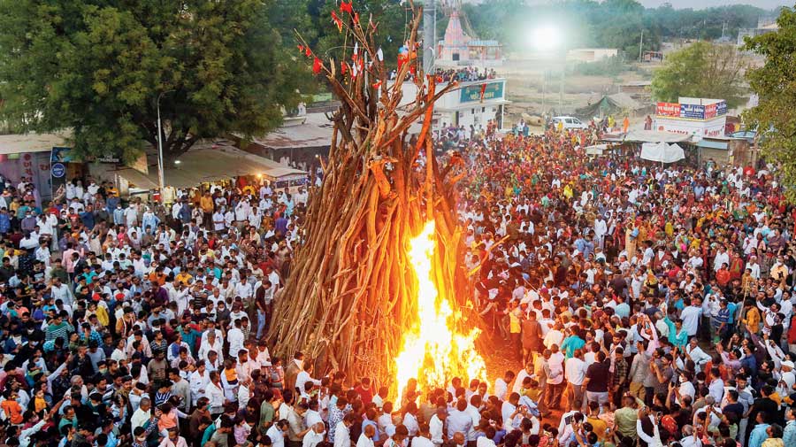 Devotees walk around a bonfire during Holika Dahan on the eve of Holi celebrations in Ahmedabad on Sunday. The  Gujarat home department had issued a notification on Wednesday banning public celebration of Holi amid a surge  in the coronavirus cases. 