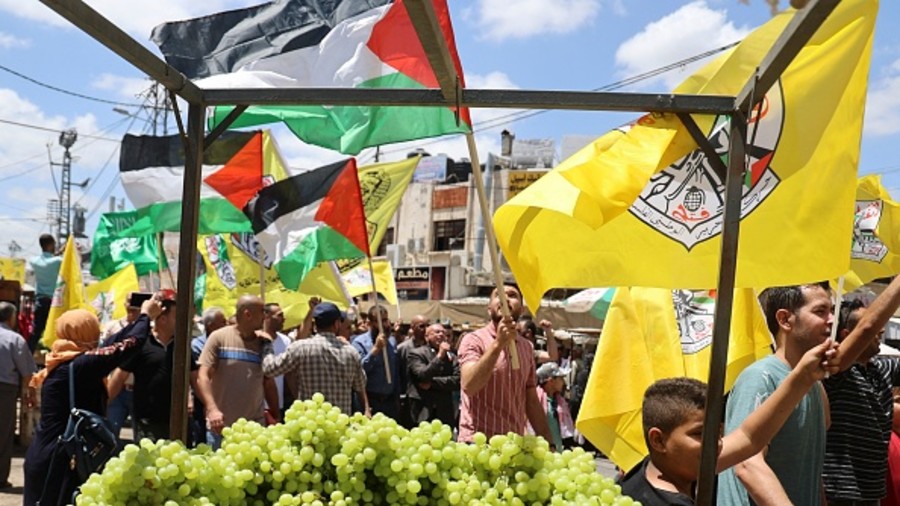 Palestinians wave flags as they take part in a rally to celebrate the ceasefire reached between the Islamist Hamas movement and Israel on Saturday