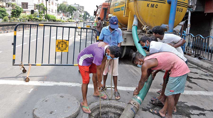 Calcutta Municipal Corporation workers clean a manhole on Central Avenue.