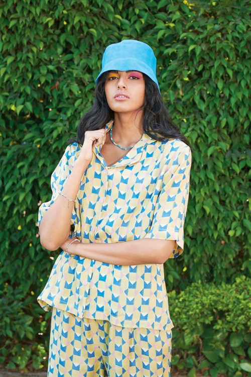 A multicoloured block-printed pyjama set in the tones of yellow, pink and blue looks soothing. The look is paired with a solid blue bucket hat with simple single-lined matching accessories.