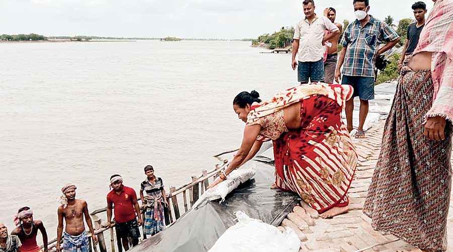 Villagers repair an embankment with sand bags and plastic sheets along the Vidyadhari river at Sandeshkhali in North 24-Parganas on Monday.
