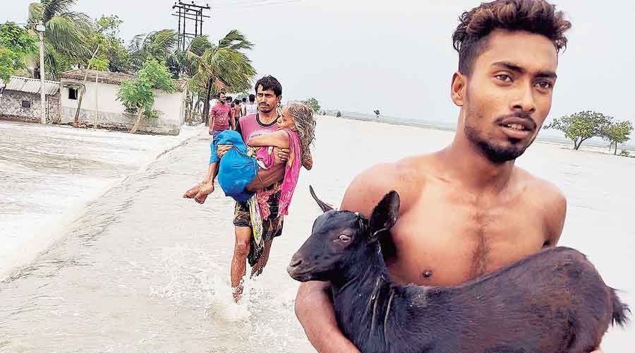 An ailing woman and a goat kid being shifted following a breach in an embankment of the Goureshwar at Hingalganj in the same district