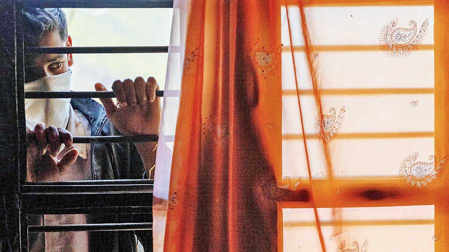 Their son Suraj Kumar, 16, watches his mother at  their home in Kaljikhal, Uttarakhand