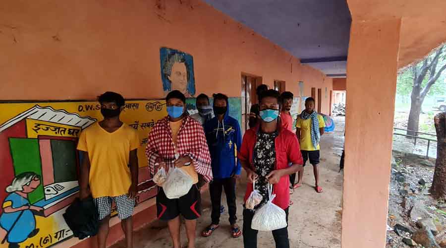 Displaced residents leave a shelter home with ration packets in West Singhbum.