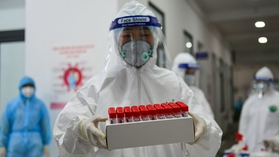 A health worker wearing personal protective equipment (PPE) carries swab samples to test for the Covid-19 coronavirus at the Thanh Xuan district medical centre in Hanoi