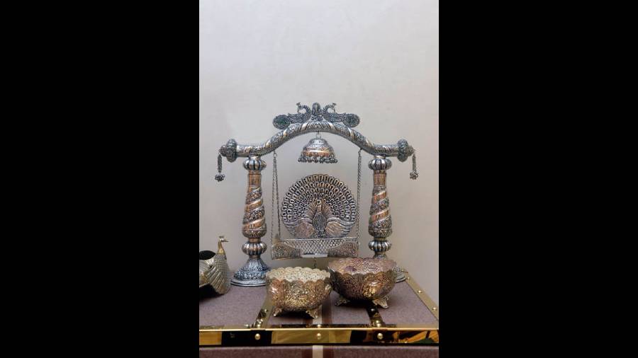 The silver singhasan with a  jhula has a large peacock motif and is intricately designed with chitai work. A perfect addition for your puja room. Rs 200,000 onwards