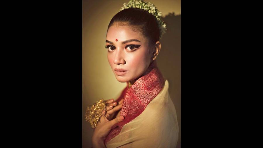 Abhijit Paul has given Sauraseni Maitra bold winged eyes, gelled-back hair and a high bun decked with flowers. Charming, so Zen and steeped in Bangaliana. “This one is inspired by a Raja Ravi Varma painting,” says Gourab Ganguli, the creative director of the project. Sauraseni is in a Parama sari, a handcrafted sandalwood organza with karwa sindoor Benarasi border, from Project & Stories.